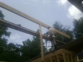 Carpenter setting a ridge beam over a new addition frame — Ice Dam Removal by Roofing Brothers in Kalona