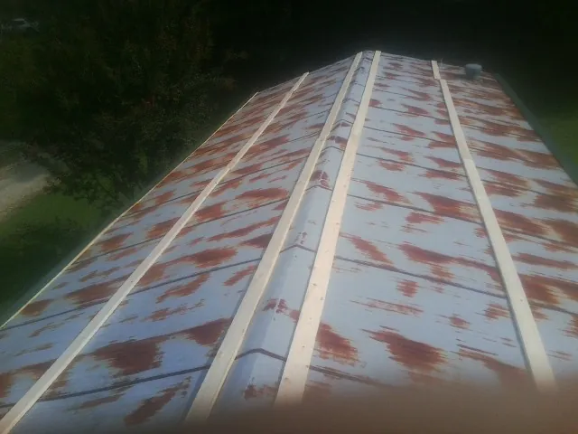 Rusted metal roof panels with new wood purlins before replacement — Storm Damage Roof Repair in Kalona by Roofing Brothers