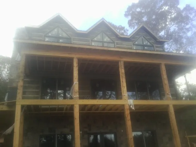Dormers and porch framing on a large log home under construction — Roof Coating work by our crew in Kalona