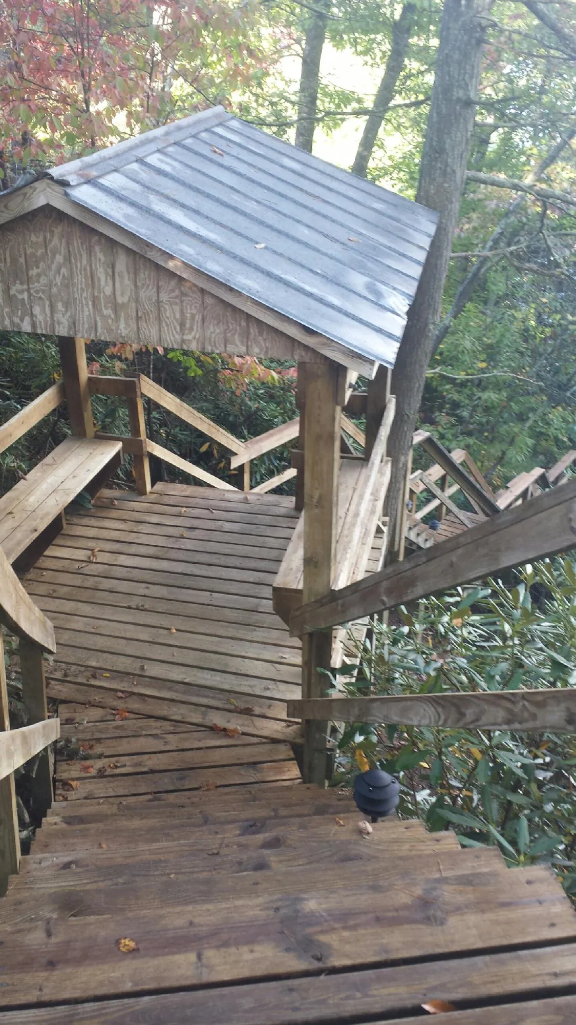 Metal roofed shelter over wooden steps on a wooded walkway — Skylight Repair & Installation work by our crew in Kalona