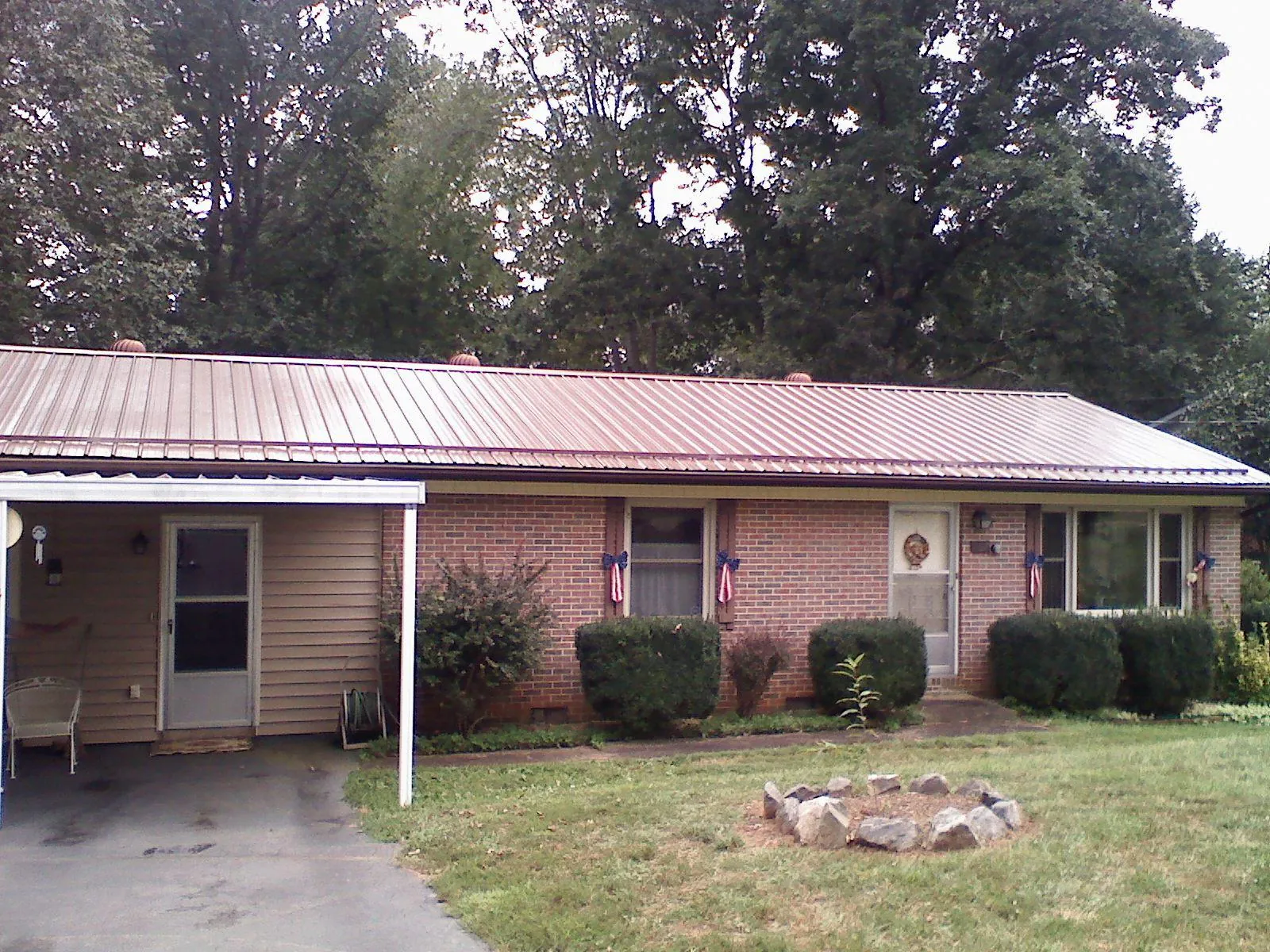 Bronze metal roof and carport on a brick ranch home — Roof Repair work by our crew in Kalona